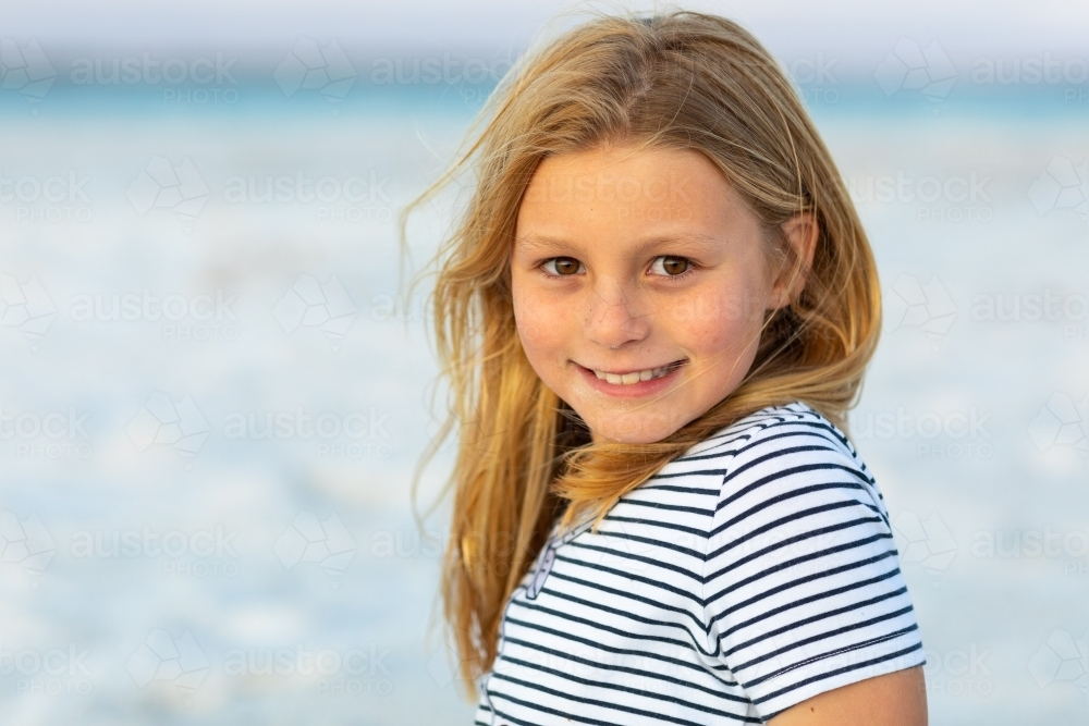 Portrait of vibrant young girl wearing striped shirt at the beach - Australian Stock Image