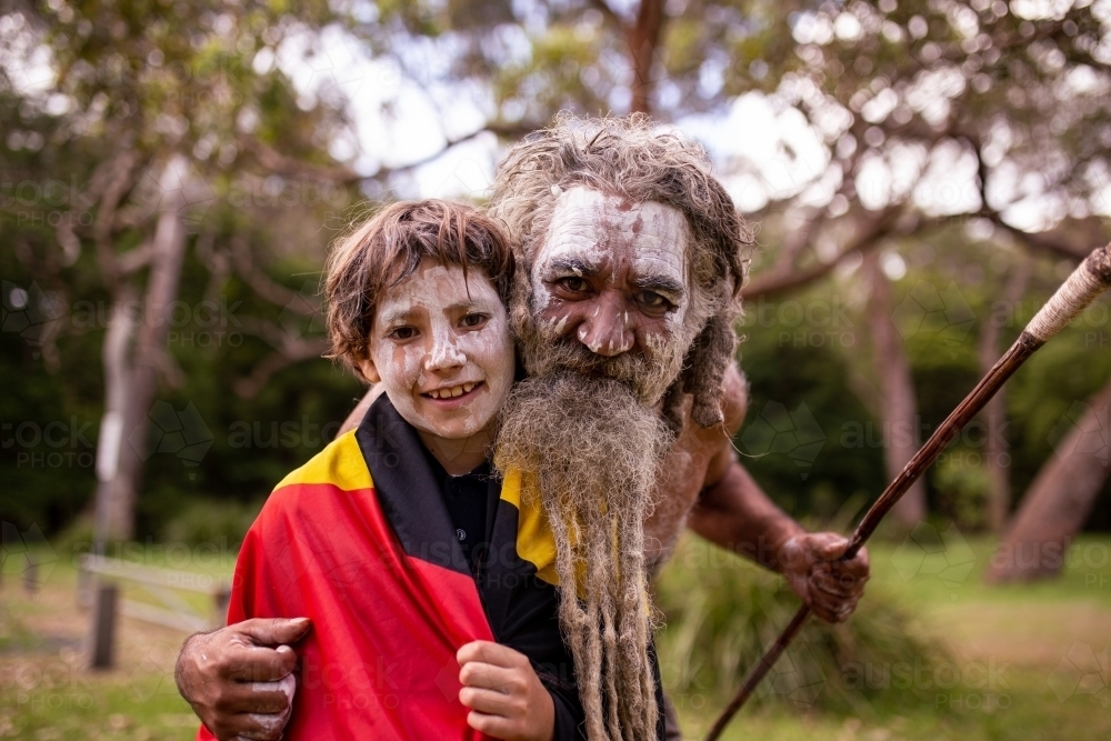 Portrait of Young Aboriginal boy wearing the Aboriginal flag with father beside - Australian Stock Image