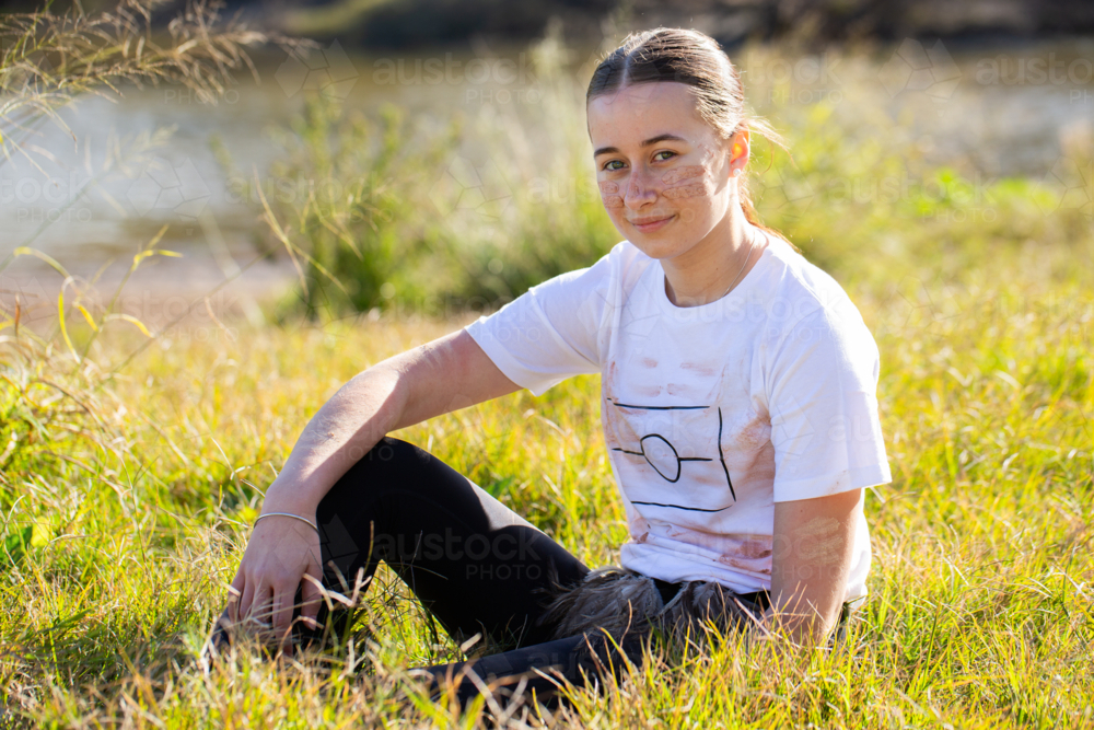 Portrait of young aboriginal person sitting in grass - Australian Stock Image
