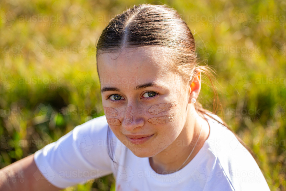 Portrait of young aboriginal person sitting in grass close up of face - Australian Stock Image