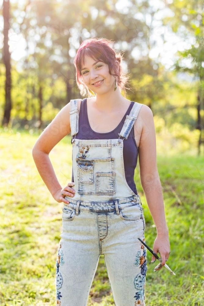Portrait of young artist hobbyist in sunlight outside holding brushes - Australian Stock Image