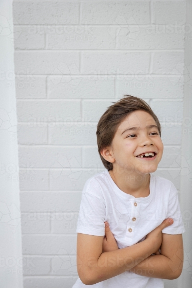 Portrait of young boy against white wall - Australian Stock Image