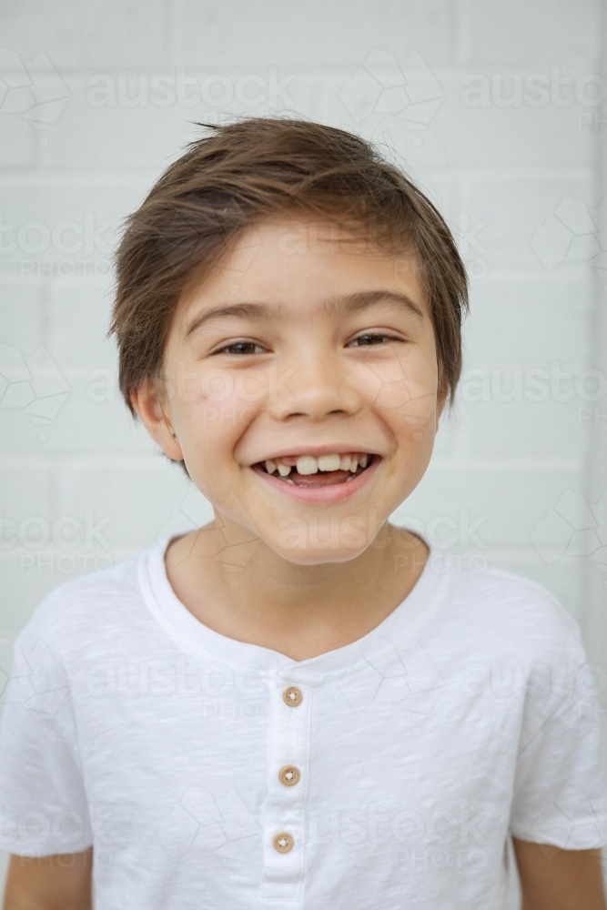 Portrait of young boy against white wall - Australian Stock Image