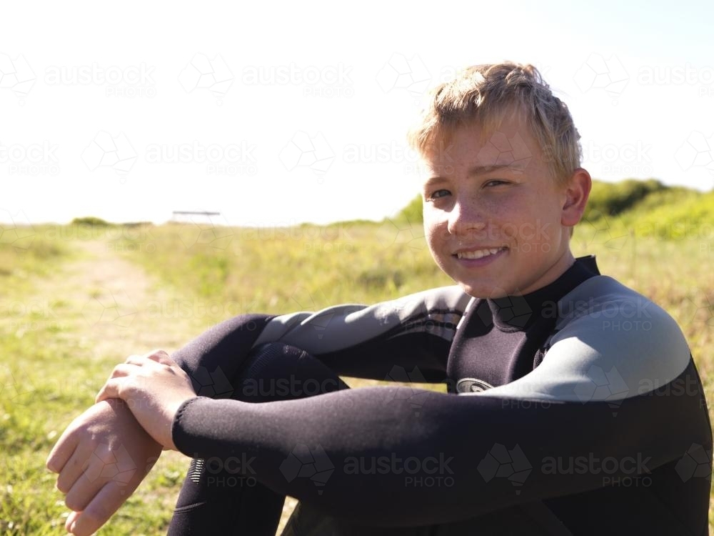 Portrait of young boy sitting in wetsuit - Australian Stock Image