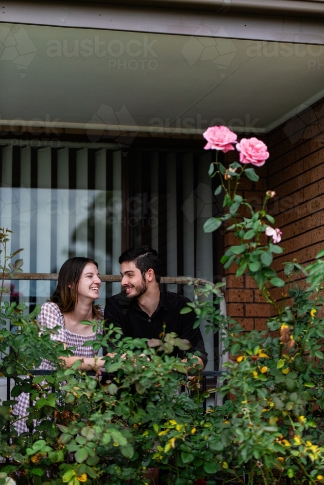 Portrait of young couple leaning on front balcony railing of home they own - Australian Stock Image
