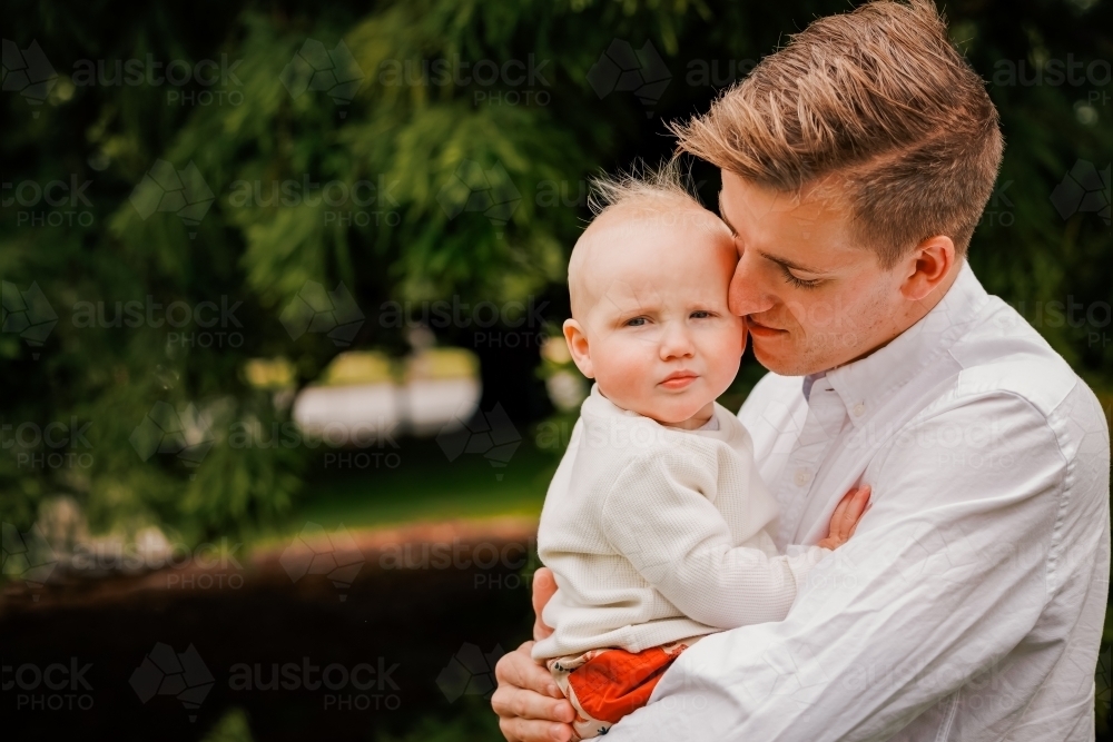 Portrait of young Dad and small baby in the park - Australian Stock Image