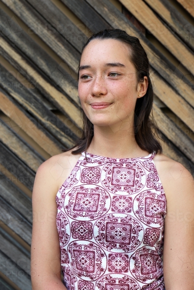 Portrait of young female outdoors with textured wooden background - Australian Stock Image