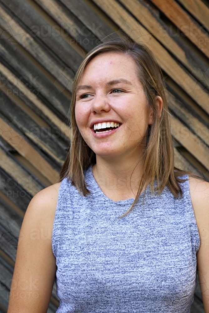 Portrait of young female outdoors with textured wooden background - Australian Stock Image