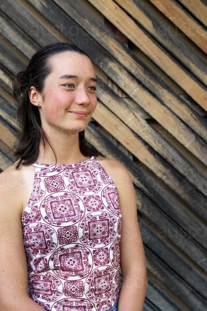 Portrait of young female outdoors with textured wooden background - Australian Stock Image
