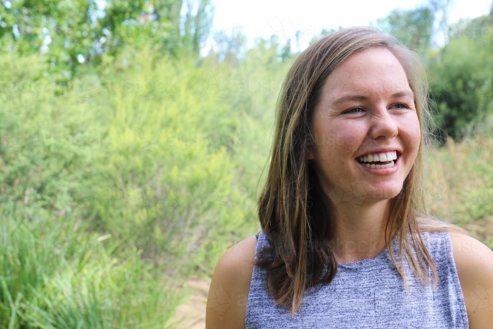 Portrait of young female outdoors with trees in background - Australian Stock Image