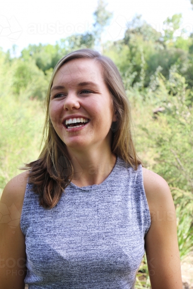 Portrait of young female outdoors with trees in background - Australian Stock Image