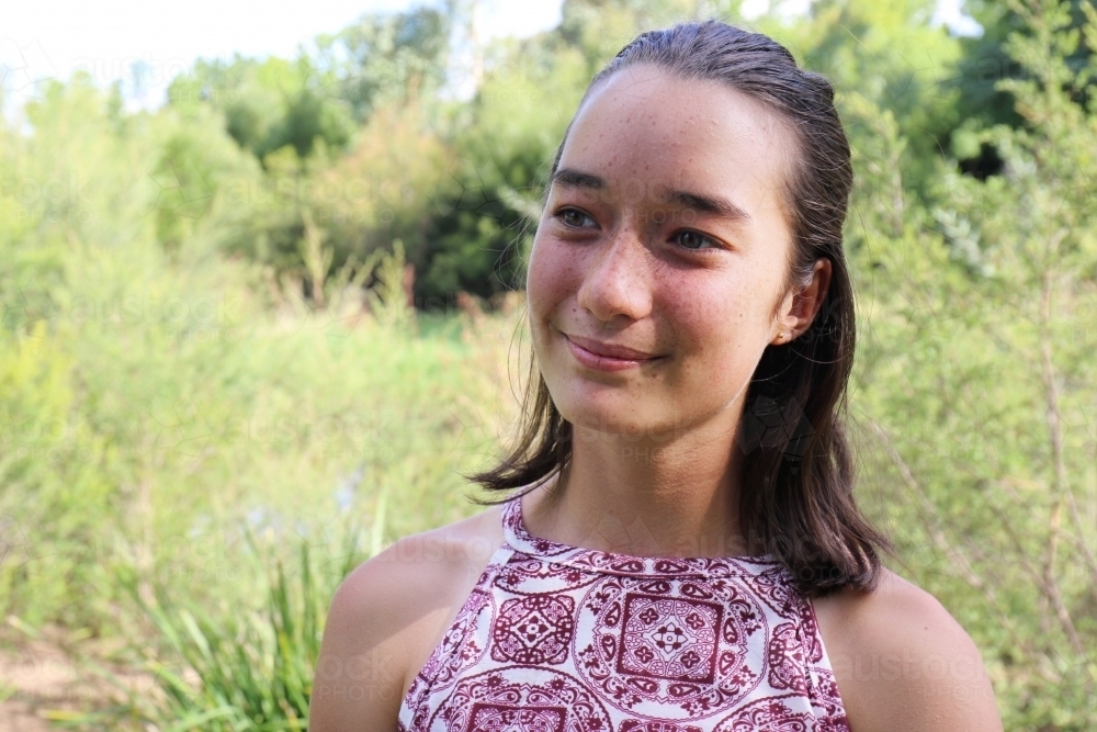 Portrait of young female outdoors with trees in background - Australian Stock Image