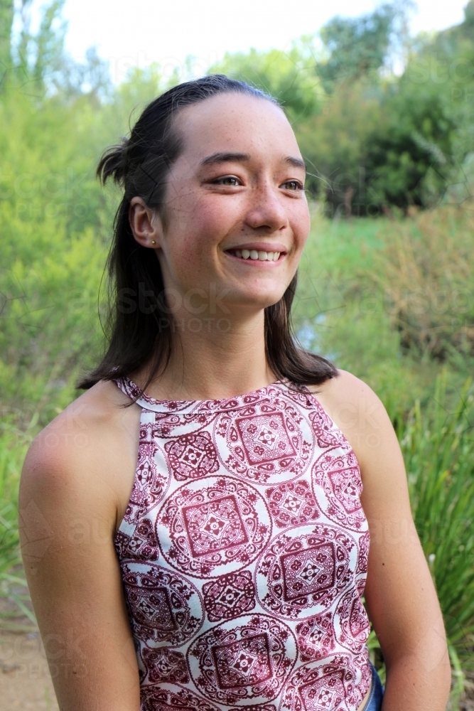 Portrait of young female outdoors with trees in background - Australian Stock Image
