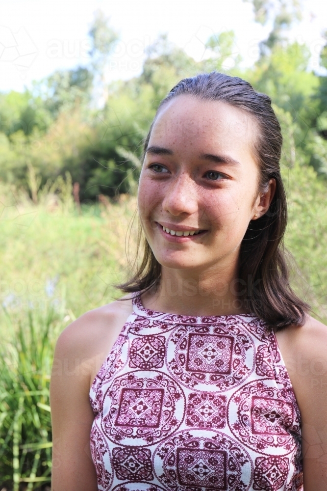 Portrait of young female outdoors with trees in background - Australian Stock Image