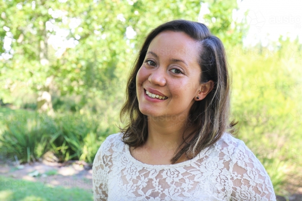 Portrait of young female outdoors with trees in background - Australian Stock Image