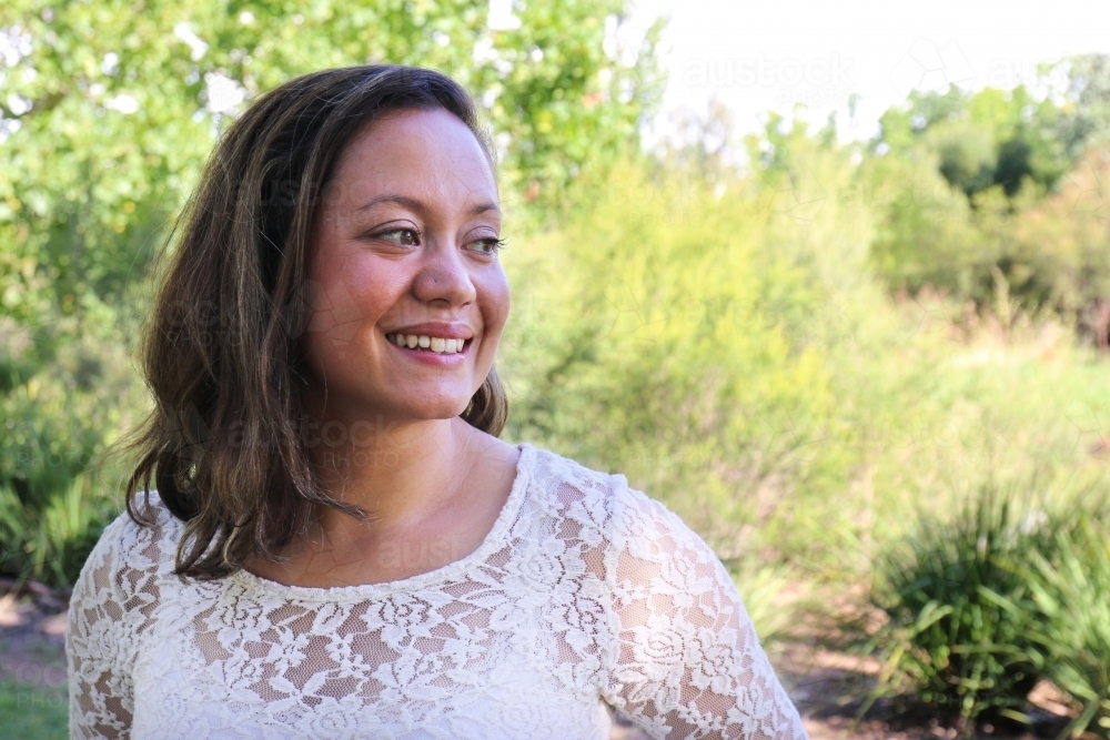 Portrait of young female outdoors with trees in background - Australian Stock Image