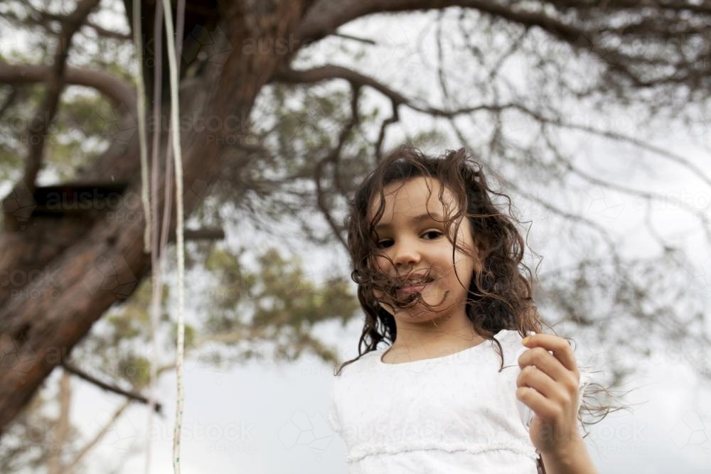 Portrait of young girl playing outside under a tree - Australian Stock Image