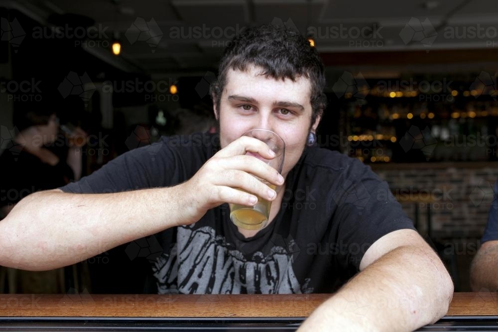 Portrait of young man having a drink at pub - Australian Stock Image
