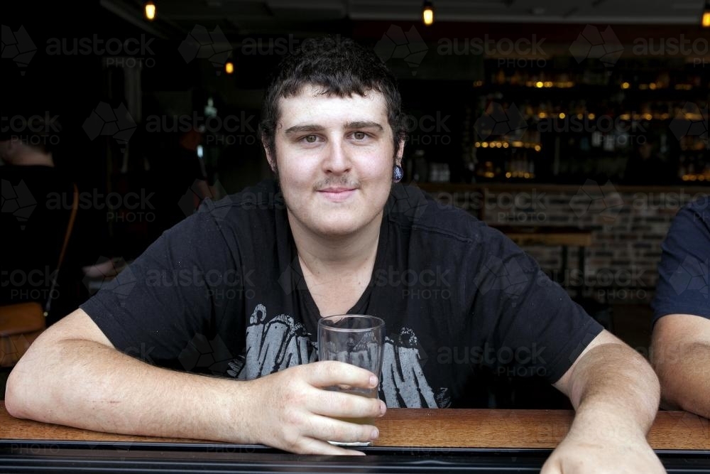 Portrait of young man having a drink at pub - Australian Stock Image