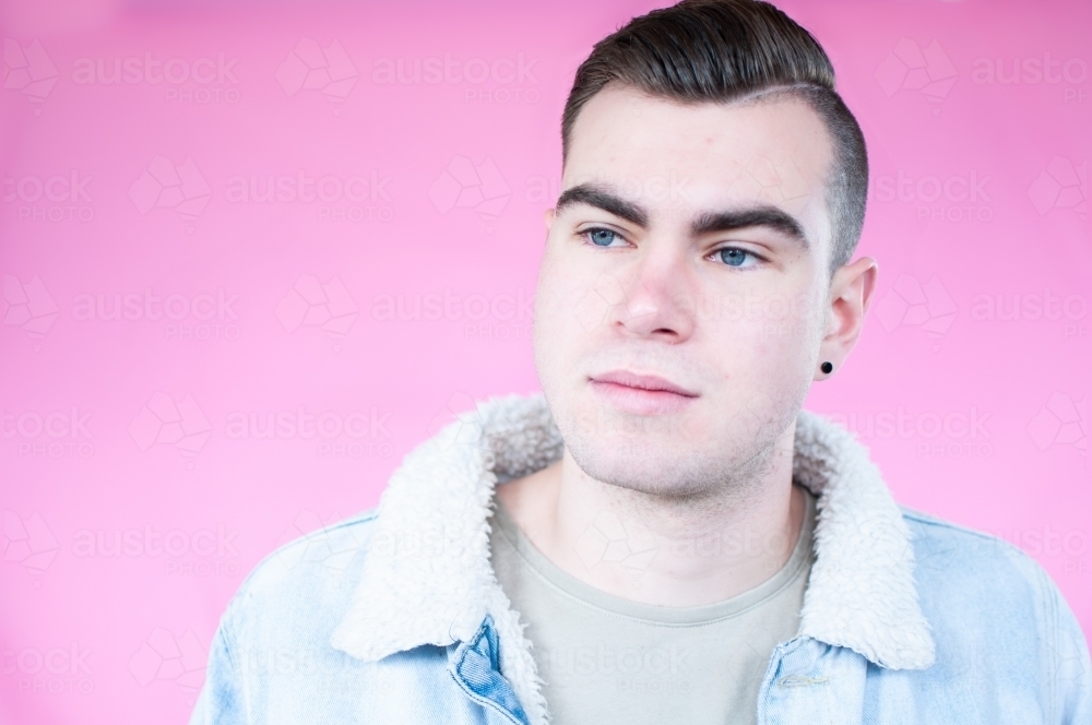 Portrait of young man on plain pink background - Australian Stock Image