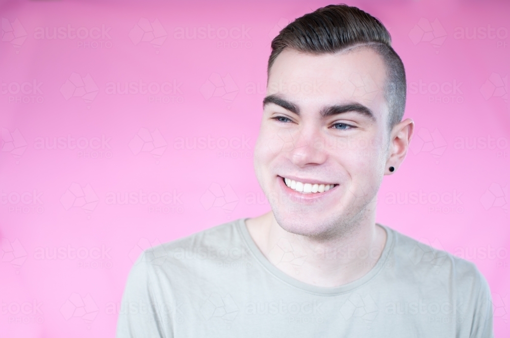 Portrait of young man on plain pink background - Australian Stock Image
