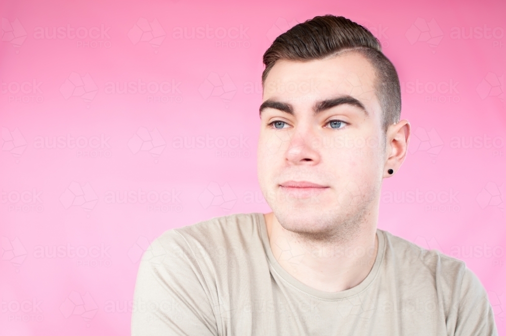 Portrait of young man on plain pink background - Australian Stock Image