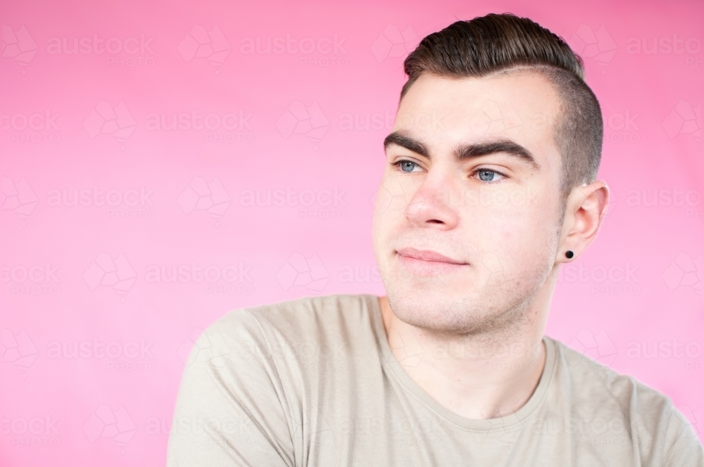 Portrait of young man on plain pink background - Australian Stock Image
