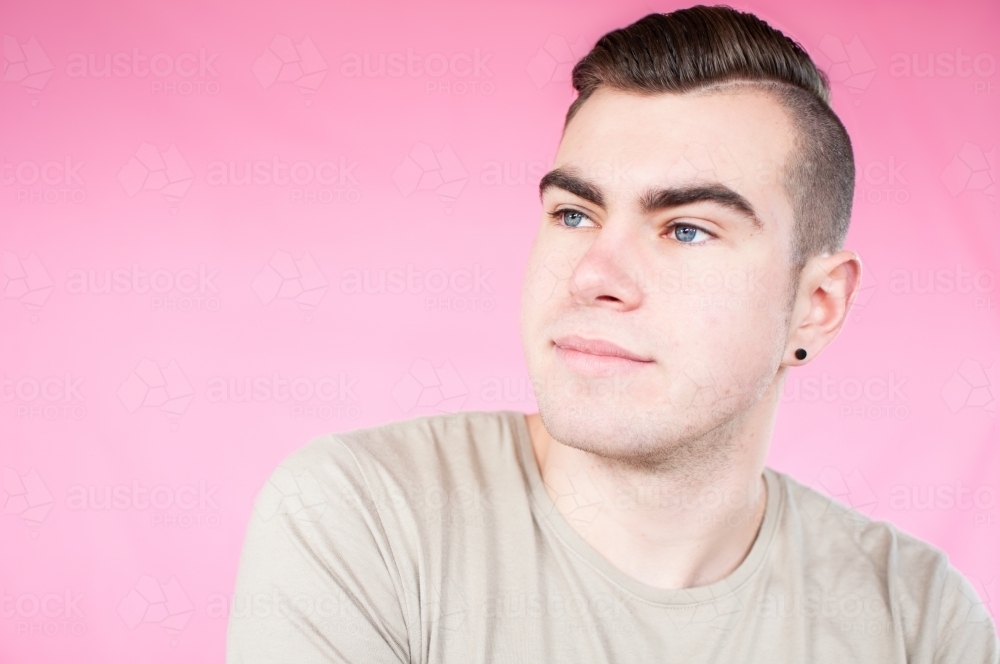 Portrait of young man on plain pink background - Australian Stock Image