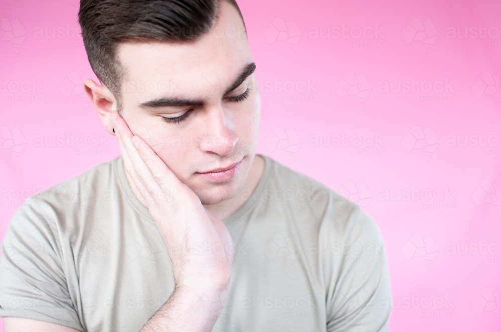 Portrait of young man with head in hand - Australian Stock Image