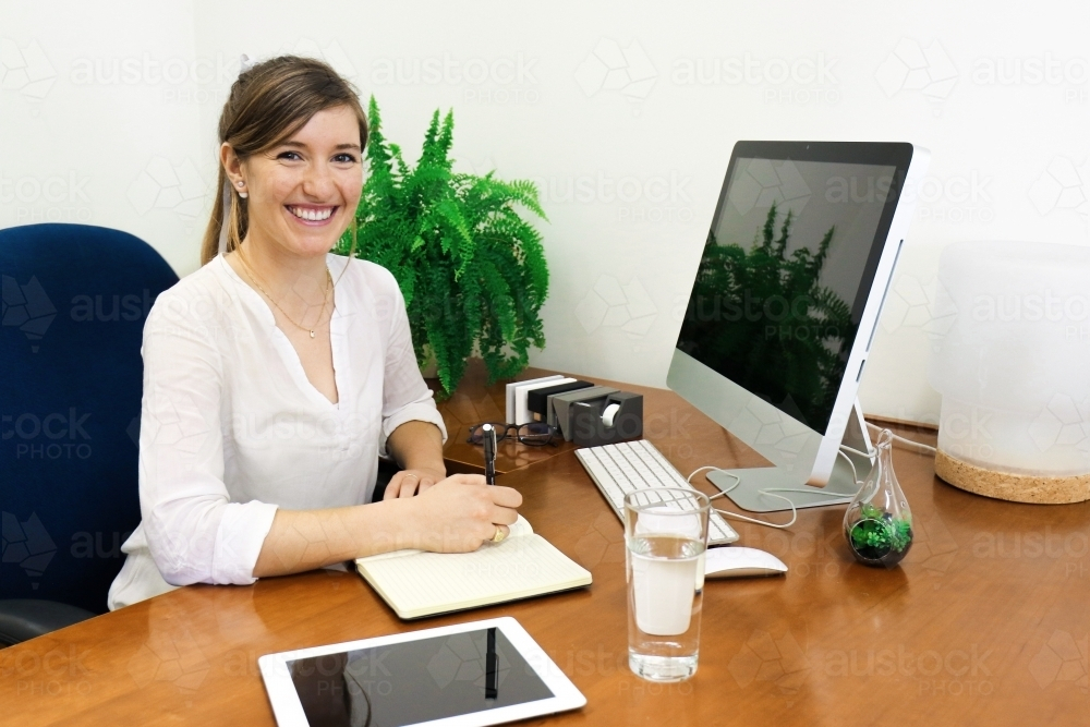 Portrait of young professional woman sitting behind her office desk - Australian Stock Image