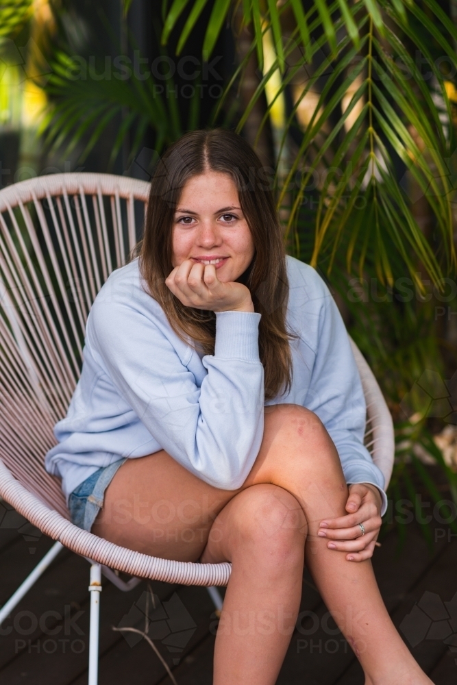 portrait of young teen girl sitting on a chair outside - Australian Stock Image
