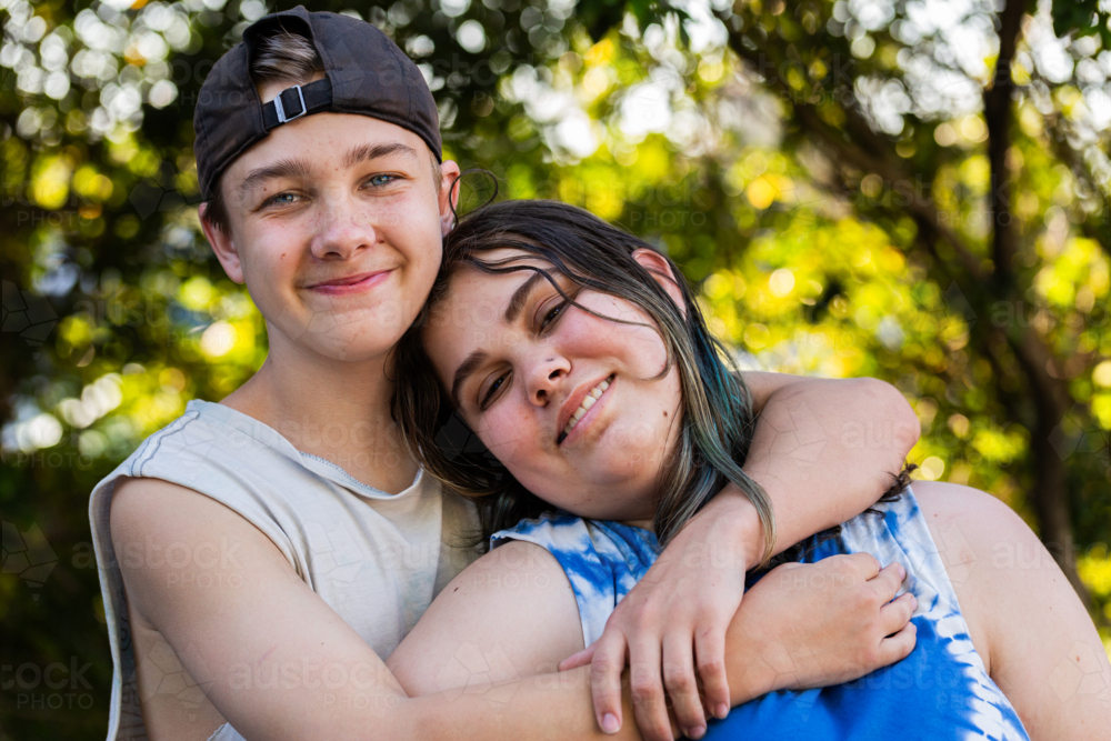 Portrait of young teenaged aboriginal Australian kids hugging one another - Australian Stock Image