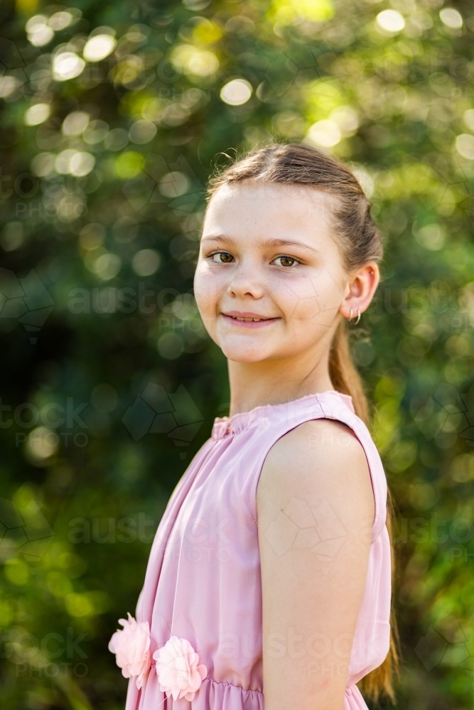 Portrait of young ten year old girl with natural green bokeh background - Australian Stock Image
