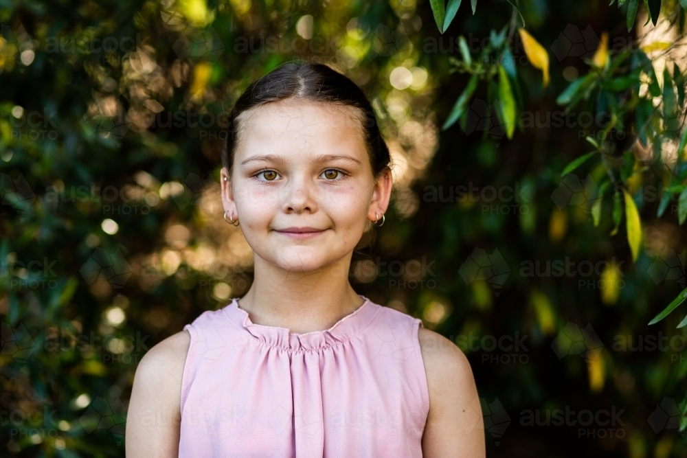 Portrait of young ten year old girl with natural green bokeh background - Australian Stock Image