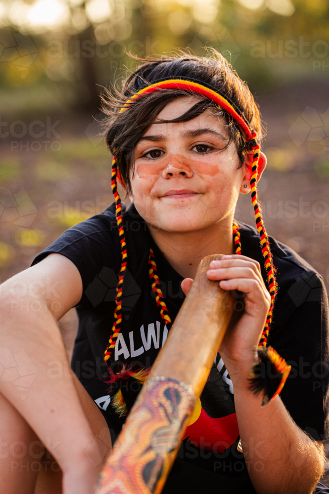 Portrait of young tween Aboriginal boy outside in rural Australia with didgeridoo - Australian Stock Image