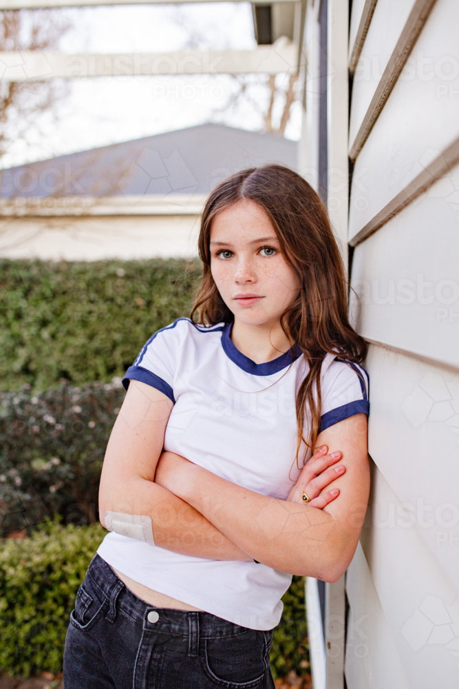 Portrait of young tween girl leaning on house wall - Australian Stock Image