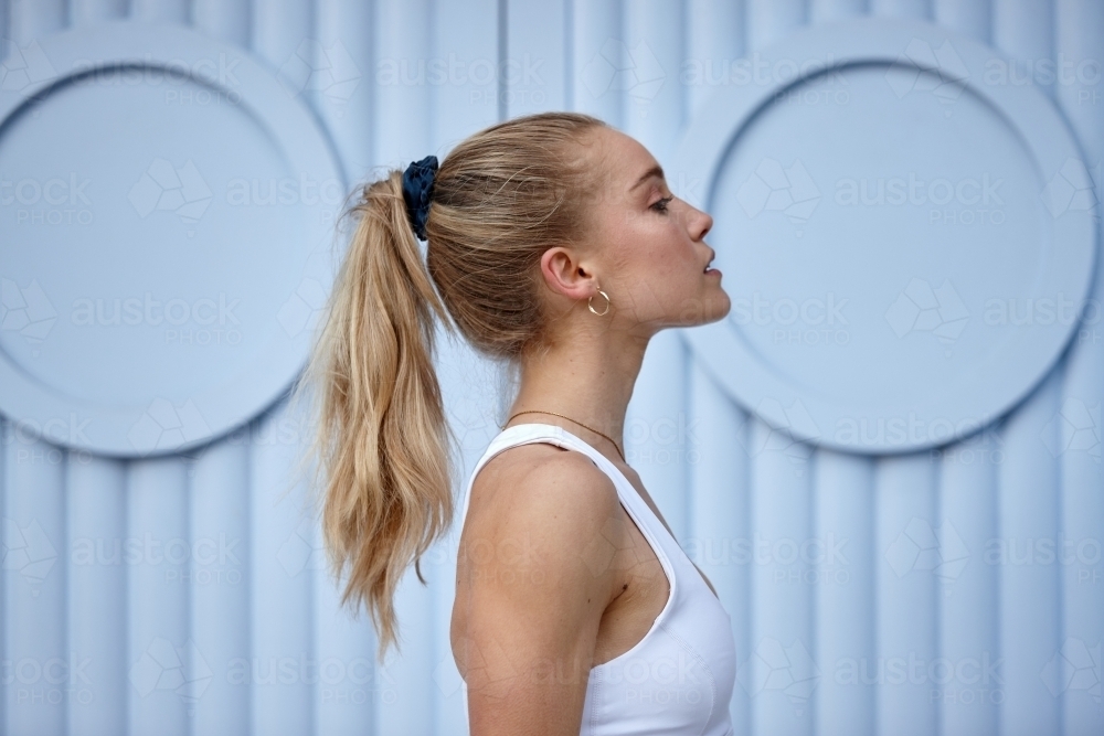 Portrait of young woman in front of blue wall - Australian Stock Image