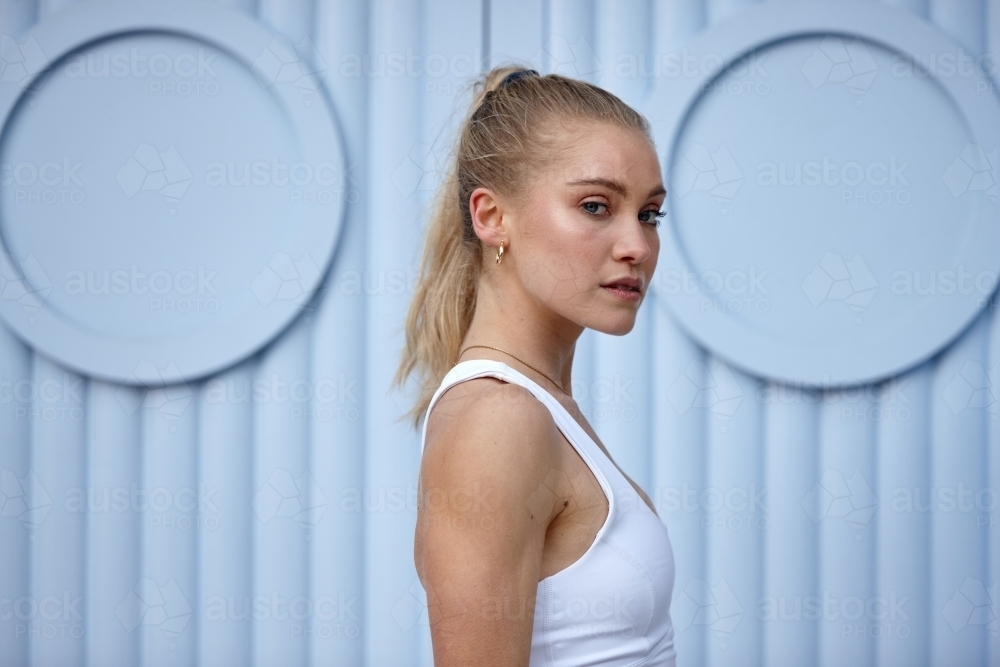 Portrait of young woman in front of blue wall - Australian Stock Image
