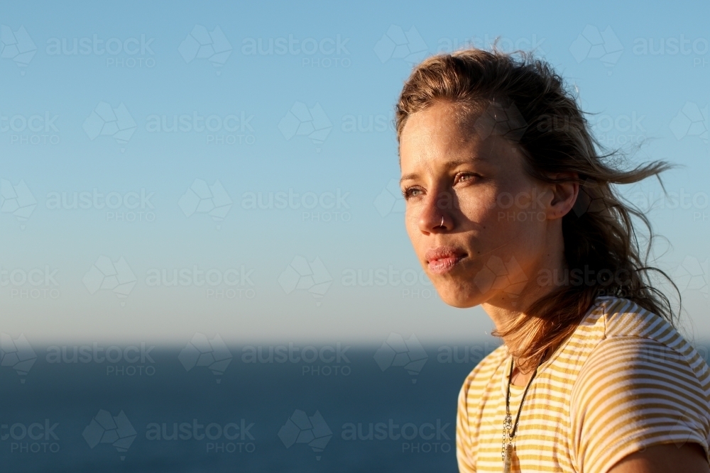 Portrait of young woman in morning sunlight by the ocean - Australian Stock Image