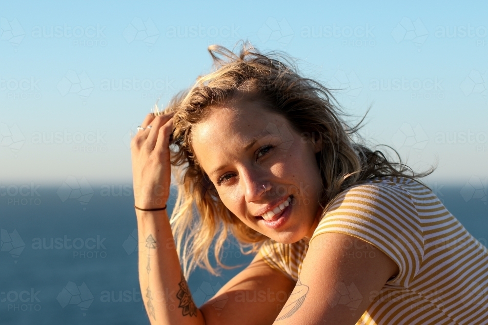 Portrait of young woman in morning sunlight by the ocean - Australian Stock Image