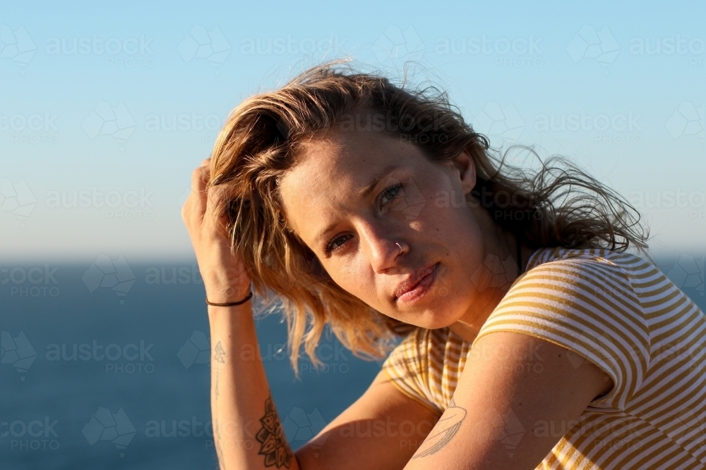 Portrait of young woman in morning sunlight by the ocean - Australian Stock Image