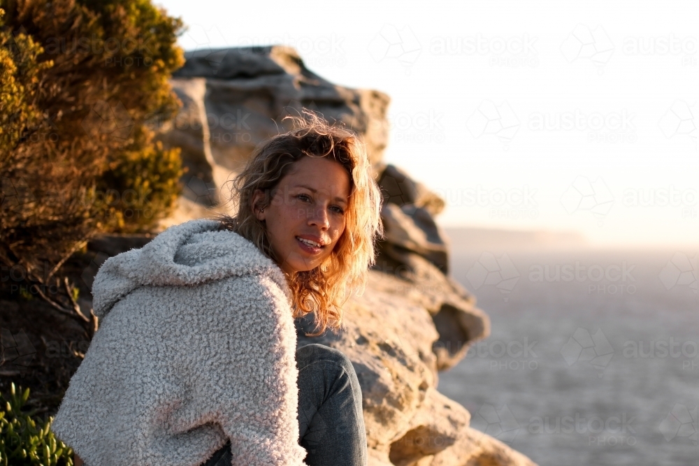 Portrait of young woman on coastal clifftop at sunrise - Australian Stock Image
