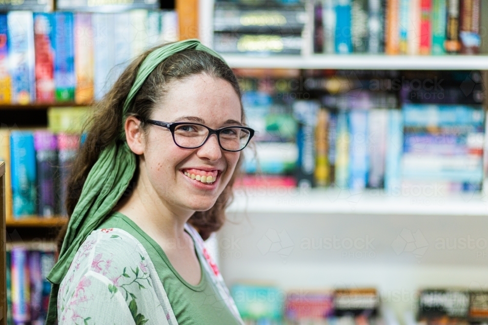portrait of young woman shopping for second hand books in a store - Australian Stock Image