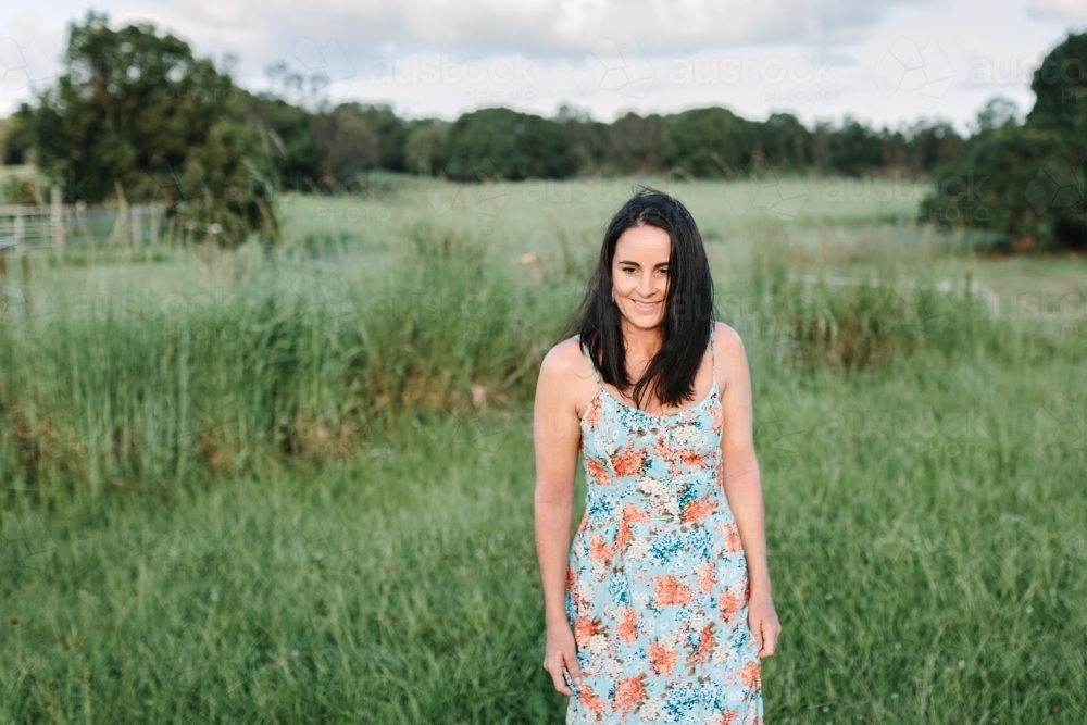 Portrait of young woman standing in a grassy field - Australian Stock Image