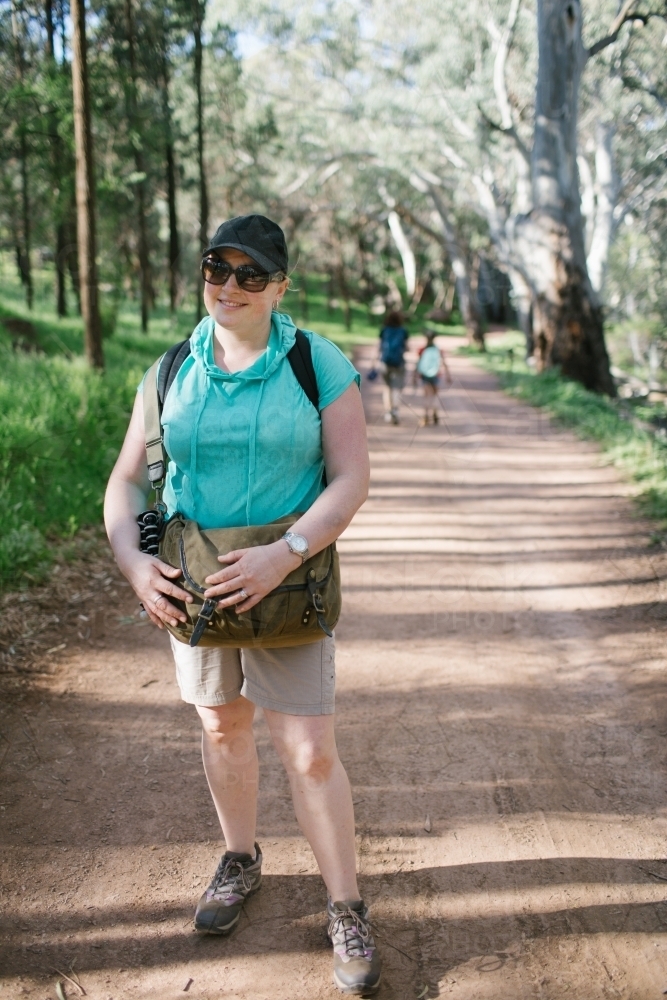 Portrait of young woman standing on a dirt path during a bush walk - Australian Stock Image