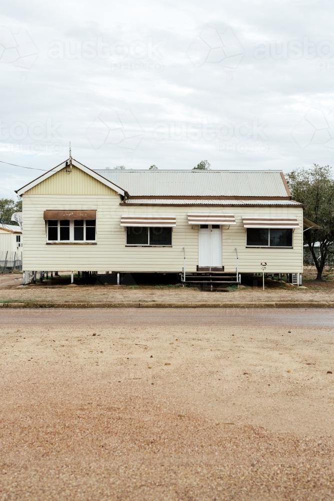 Portrait photo of cream coloured Queenslander House with brown trimming - Australian Stock Image