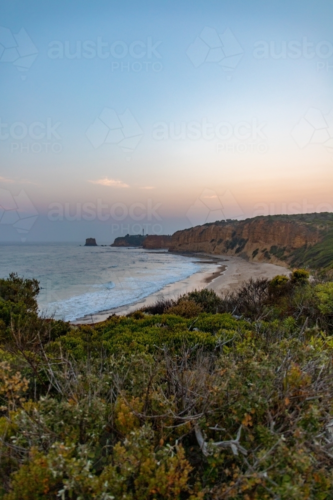 portrait view along coastline with lighthouse in the distance - Australian Stock Image