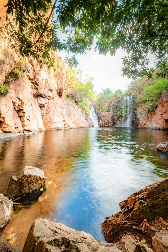 Portrait view of Florence Falls being framed by rocks and overhanging branches : Austockphoto Portrait view of Florence Falls being framed by rocks and overhanging branches - Australian Stock Image