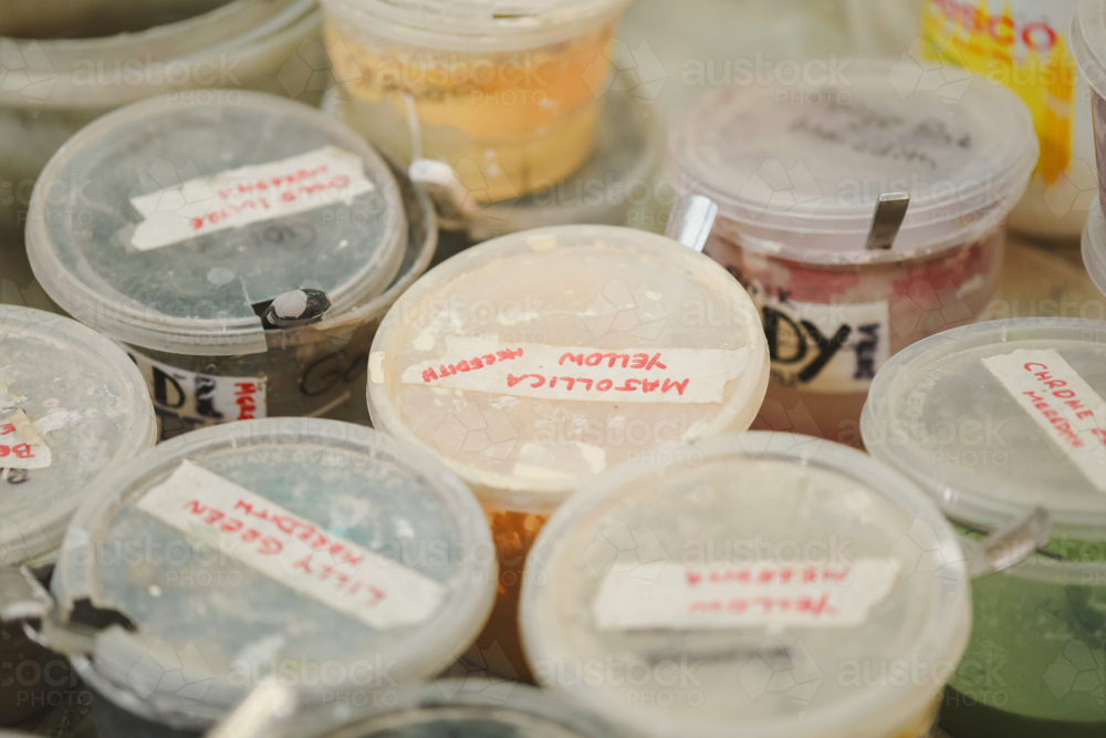 Pottery glaze containers labelled with colours on a shelf in a ceramics studio - Australian Stock Image
