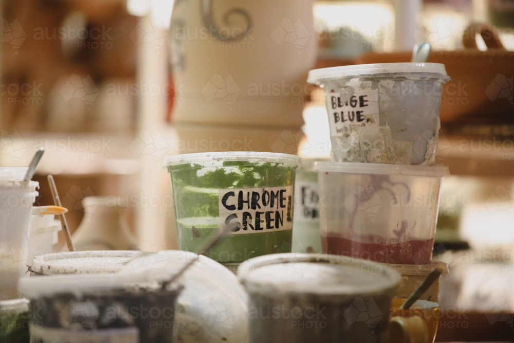 Pottery glaze containers labelled with colours on a shelf in a ceramics studio - Australian Stock Image